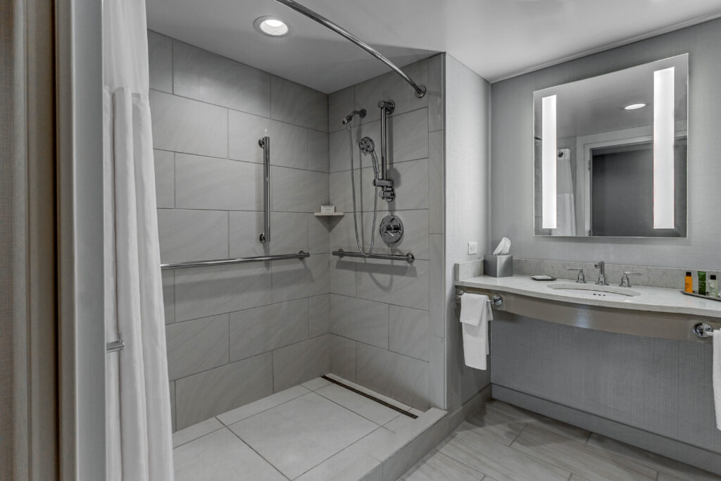 Shower with accessibility safety rails and a bathroom vanity.